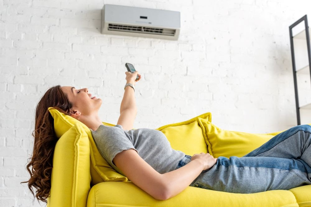 Femme sur un canapé sous un climatiseur 